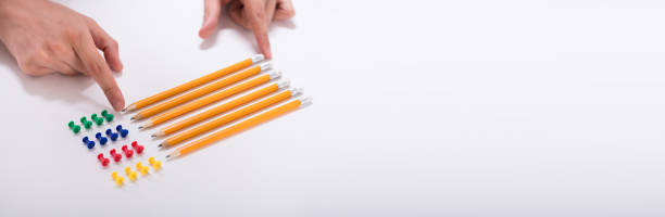 istock Person's Hand Arranging Pencils And Multi Colored Pushpins 1226428897