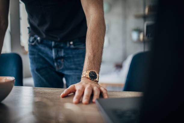 istock Man with hand on table has a gold wristwatch 1226432353