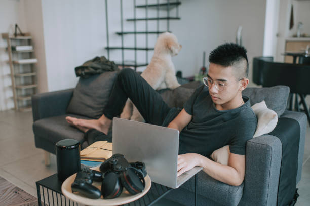 um adolescente asiático escola em casa estudando em casa na sala de estar usando laptop - dog school audio - fotografias e filmes do acervo