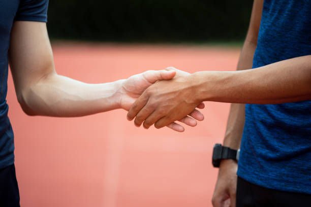 nahaufnahme von zwei asiatischen läufer hand schütteln in laufstrecke - greeting teenager handshake men stock-fotos und bilder