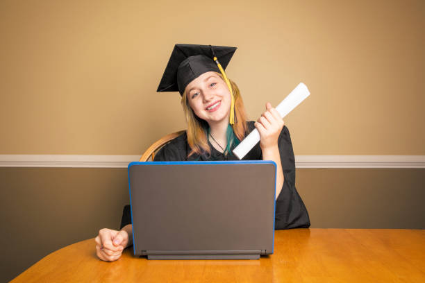 graduada femenina en casa con computadora portátil - online degree fotografías e imágenes de stock