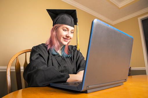 A high school girl graduating on her laptop during the coronavirus pandemic.
