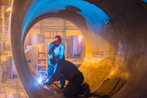 Two welders work in a pipe for an oil pipeline.