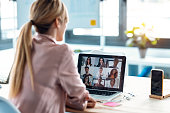 Female employee speaking on video call with diverse colleagues on online briefing with laptop at home.