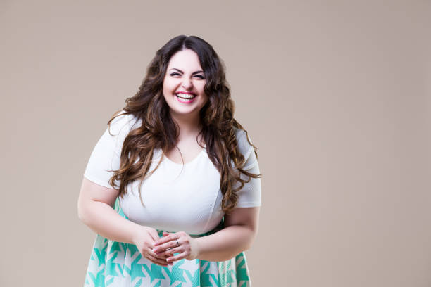 laughing happy plus size model in casual clothes, fat woman on beige background - body positive imagens e fotografias de stock