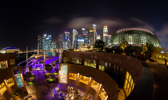 The Esplanade Theater at night with Singapore skyline in the background. The iconic building on Marina Bay contains a concert hall, a public library and a shopping mall.