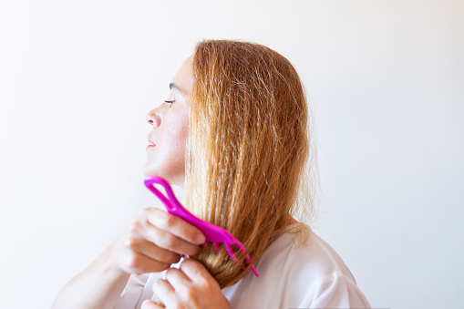Woman brushing her hair with a pink hair comb