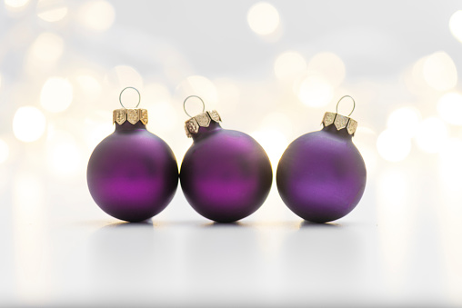 Purple Christmas baubles on shiny background.