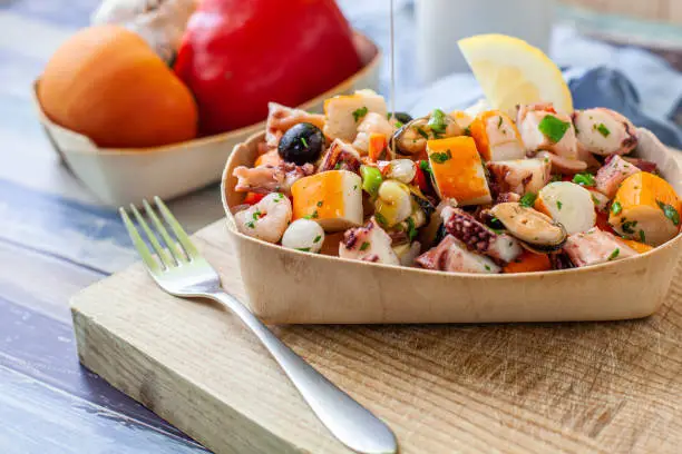 Dipping olive oil on homemade seafood salad on wooden tray