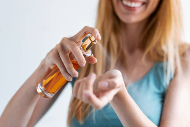 istock Smiling young woman applying perfume on her wrist while standing at home. 1226446998