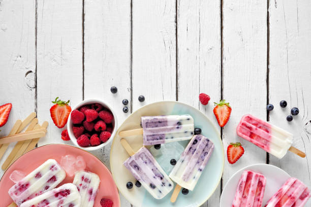 istock Assorted berry fruit yogurt popsicle table scene border, top view on a white wood background 1226448833