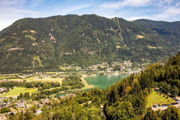 panorama desde el lago ossiacher con la montaña gerlitzen al fondo en el tiempo soleado en carintia, austria, europa - paragliding sport austria parachuting fotografías e imágenes de stock