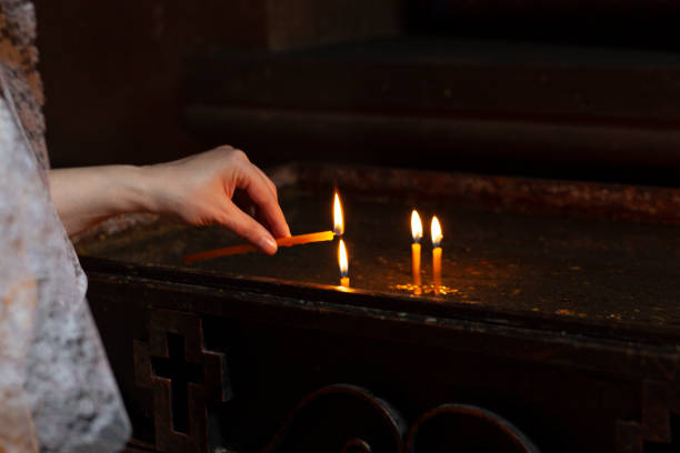 istock woman light a candle in church 1226454286