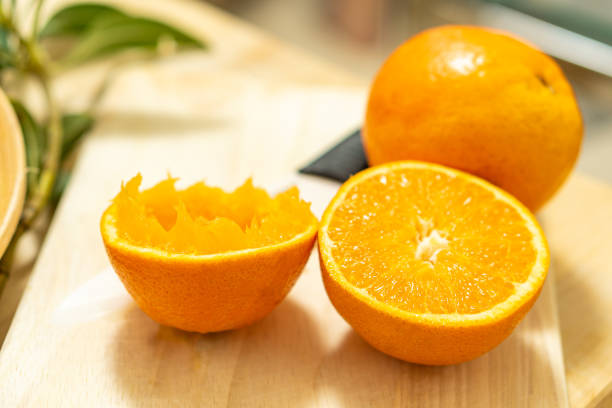 istock an orange split in half and with one of the parts squeezed 1226455900