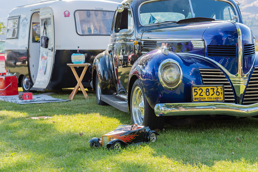 Penticton, British Columbia/Canada - June 22, 2019: classic car and vintage camper trailer on display at the Beach City Peach Cruise, one of the largest car shows in North America. The event runs annually beside Okanagan Lake in June.