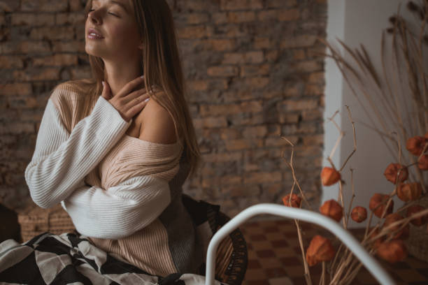 une jeune femme attirante s’assied dans une chaise dans une position détendue. - joy the human body smiling women photos et images de collection