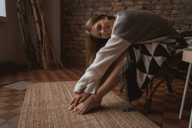 une jeune femme attirante s’assied dans une chaise dans une position détendue. - joy the human body smiling women photos et images de collection