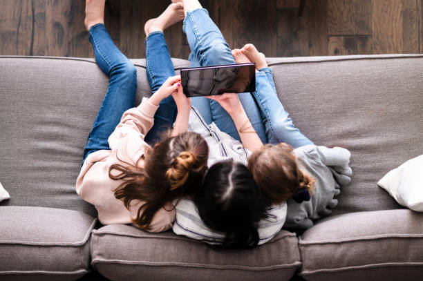 istock Mom and daughters watch something on digital tablet 1226458536