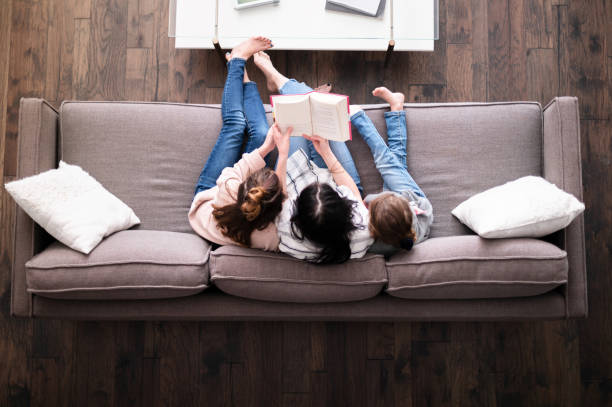 high angle view of family reading together - child reading mother book imagens e fotografias de stock