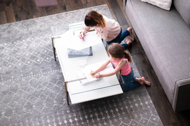 istock Sisters work on schoolwork at coffee table in living room. 1226458710