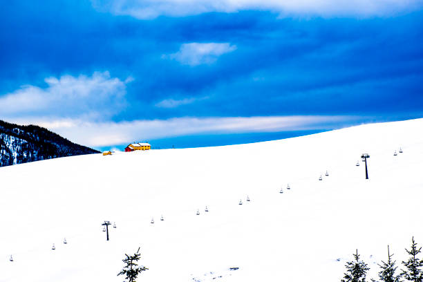 Alpine snowy landscape with hut, clouds and mountain peaks, on the Asiago plateau in the province of Vicenza, Italy