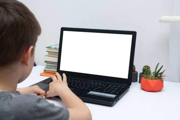 istock A boy sits at a desk with a laptop. Online Home Learning Concept. Mock up laptop. 1226462011