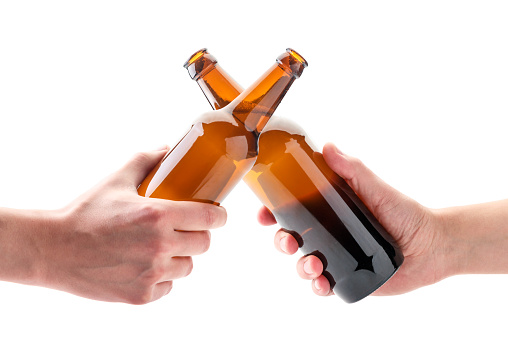 Two hands with beer bottles clink glasses on a white background. Isolated