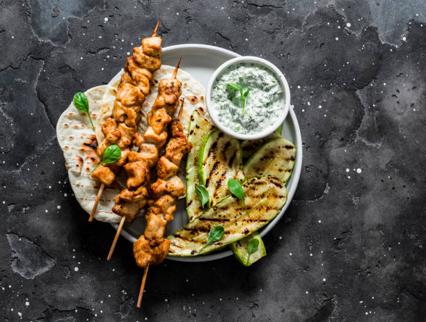 chicken skewers souvlaki, grilled zucchini, tortillas and tzadziki sauce - delicious greek style lunch on a dark background, top view - souvlaki imagens e fotografias de stock