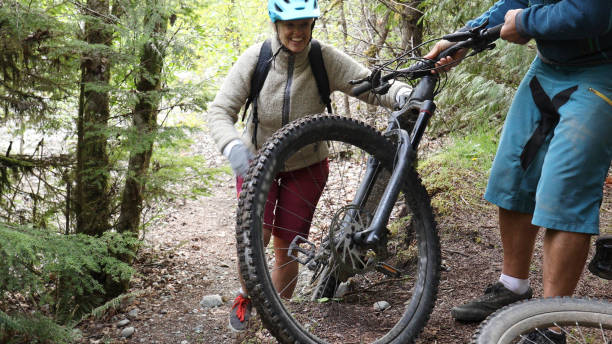 istock Man helps push mountain e-bikes up steep forested trail 1226467900