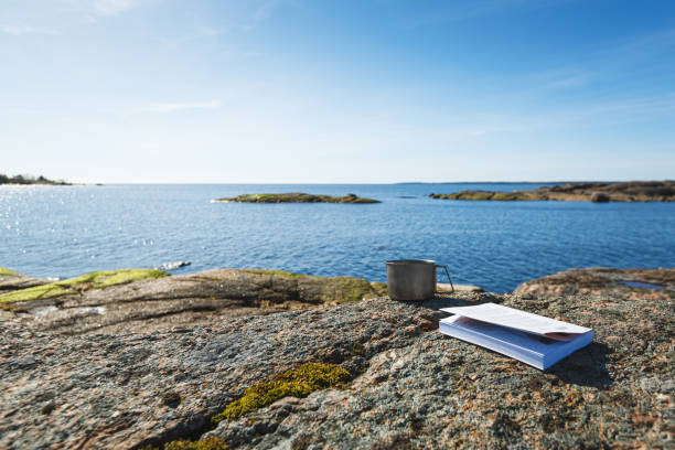istock A mug with a book on a stone seashore. Cup in focus, blurred background. 1226467930
