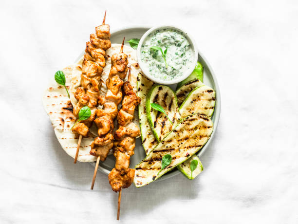 Chicken skewers souvlaki, grilled zucchini, tortillas and tzadziki sauce - delicious greek style lunch on a light background, top view Chicken skewers souvlaki, grilled zucchini, tortillas and tzadziki sauce - delicious greek style lunch on a light background, top view chicken skewer stock pictures, royalty-free photos & images