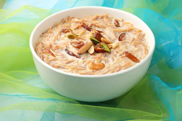 Khir or kheer payasam also known as Sheer Khurma Seviyan consumed especially on Eid or any other festival in india/asia. Served with dry fruits toppings in a bowl over colourful background.