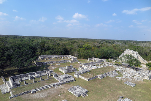 Mayapan, Yucatan, Mexico - Jan. 28, 2020: The Mayan ruins at Mayapan, seen from the top of the Temple of Kukulcan pyramid, the tallest structure at the site located 35 miles southeast of Merida, bask in the mid-day sun.  Mayapan was the Mayan capital of the Yucatan peninsula from approximately 1200 A.D. to 1400 A.D.