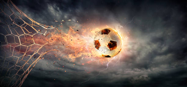 Fiery Soccer Ball breaking through The Net With Dramatic Sky Sphere In Goal - Fiery Soccer Ball breaking through The Net With Dramatic Sky breaking photos stock pictures, royalty-free photos & images