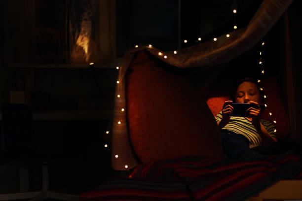 istock Kid boy watching movie on smart phone in bed 1226476994