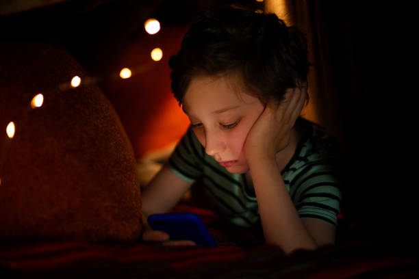 istock Kid boy watching movie on smart phone in bed 1226477007