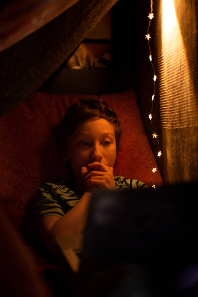 istock Kid boy watching movie on smart phone in bed 1226477010