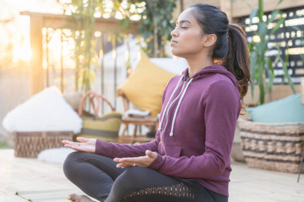 Southeast Asian female doing yoga on her deck during sunset Beautiful mixed race female in her 20's doing relaxing yoga in her backyard while the sunsets behind her. teen yoga stock pictures, royalty-free photos & images