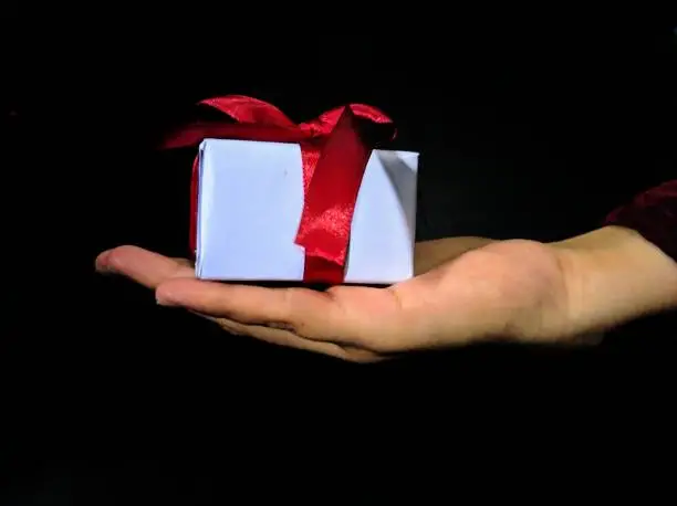 hands holding a red-ribbon gift box