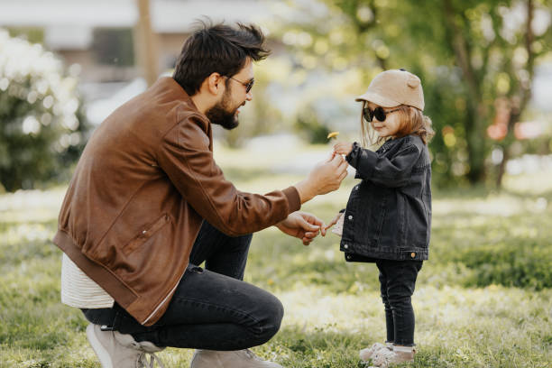 giovane padre e figlia spensierati che camminano nella giornata primaverile. - action family photograph fathers day foto e immagini stock