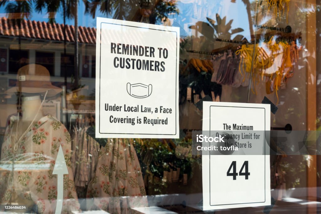 Face mask required and maximum occupancy sign Face mask required and maximum occupancy sign in a retail storefront to prevent the spread of COVID-19. Protective Face Mask Stock Photo