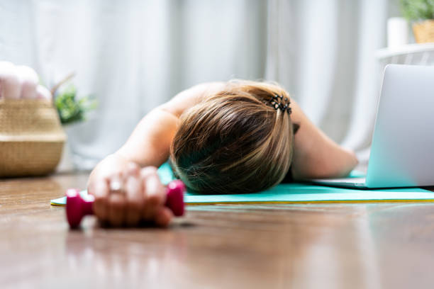 Woman falling asleep. Tired after exercise and workout. Overtraining concept. Exhausted woman lying on floor and resting after heavy cardio training in home gym at yoga mat. mujer durmiéndose. cansado después del ejercicio y el entrenamiento. concepto de sobreentrenamiento. mujer agotada acostada en el suelo y descansando después de un entrenamiento cardiovascular pesado en el gimnasio en el gimnasio en el estera de yoga
