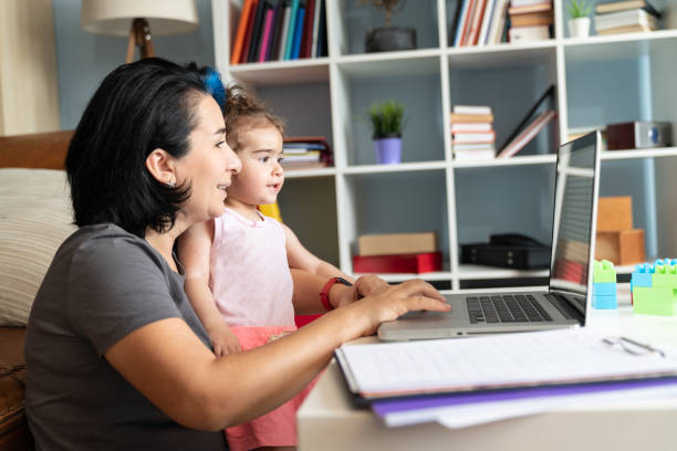 istock Mother Holding Her baby Daughter And Working At Home Using Laptop 1226487622