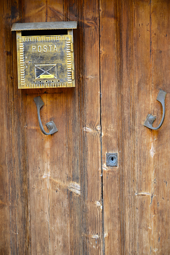 old metal mailbox mounted on wooden door