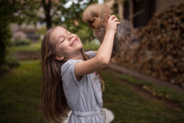 istock Smiling girl holding a puppy in backyard 1226489410