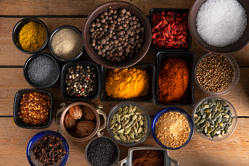 Many different shapes of bowls full of spices on a wooden surface