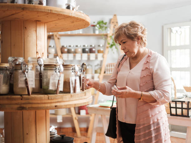 Hispanic senior woman shopping in zero waste store A hispanic senior woman standing and shopping for spices in zero waste store. local products stock pictures, royalty-free photos & images