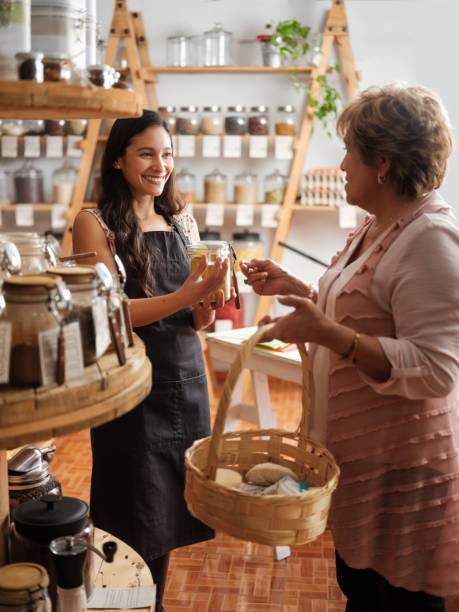 happy employee helping hispanic customer in sustainable store - small business built structure retail imagens e fotografias de stock