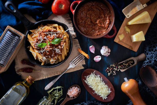 istock Penne with Bolognese sauce in serving size casserole with ingredients in rustic pots 1226502729