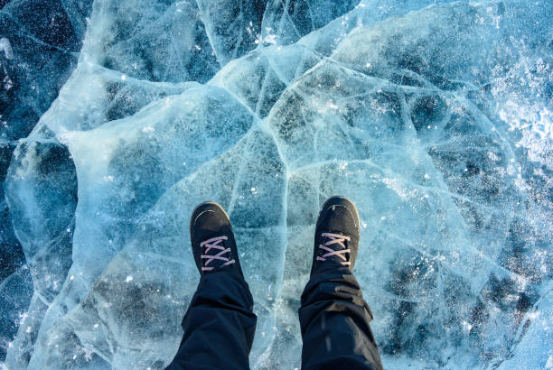 un pie de turista de pie en la superficie de grietas del lago congelado baikal en la temporada de invierno de siberia, rusia. - thick snow fotografías e imágenes de stock